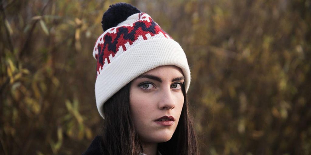 Retrato de una mujer con un gorro de punto blanco y rojo en un entorno arbolado