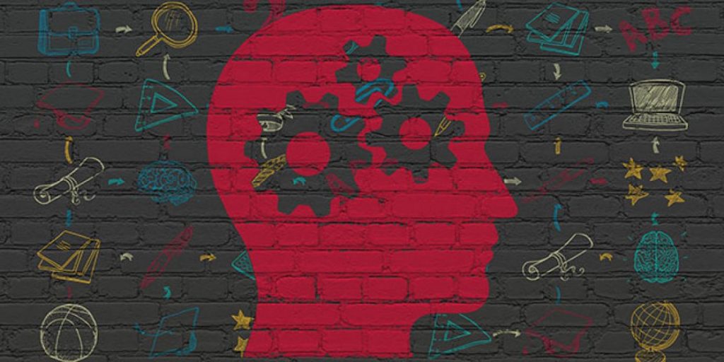 Silueta roja de una cabeza con engranajes, rodeada de dibujos relacionados con el aprendizaje sobre una pared de ladrillo.