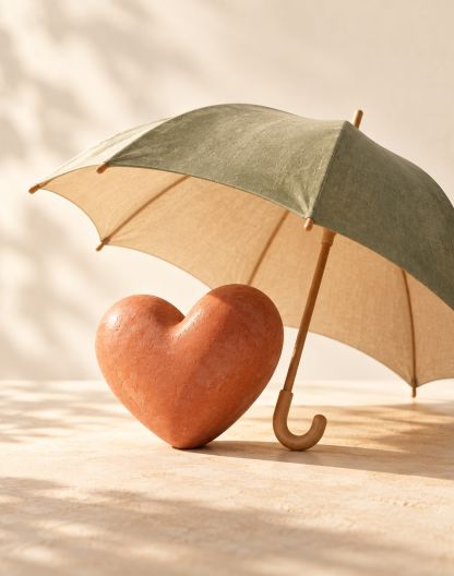 Un corazón de terracota bajo un paraguas abierto.